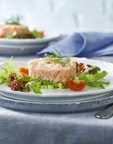 Räucherlachs-Tatar auf Avocado auf Teller.