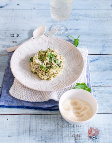 Spinatrisotto auf Teller mit Parmesan in Schälchen