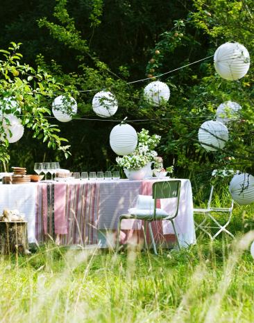 Mittsommerfest im Freien mit Tischen, Stühlen und Girlanden.