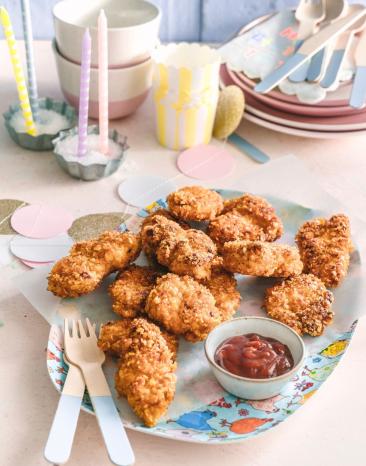 Chicken Nuggets auf einem Teller vor Partydekoration.