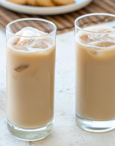 Thailändischer Eistee in zwei Gläsern mit Eiswürfeln.