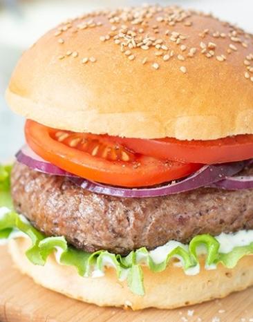 Hamburger mit Tomaten auf einem Bettchen.