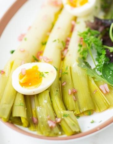 Lauchsalat mit Himbeer-Vinaigrette und zwei halbe Eier auf einem Servierteller.