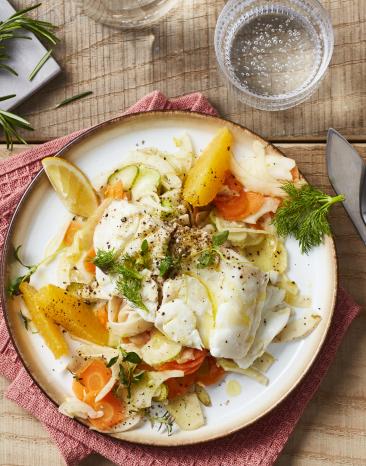 Fisch mit Gemüse und Orangenfilets auf einem Teller-