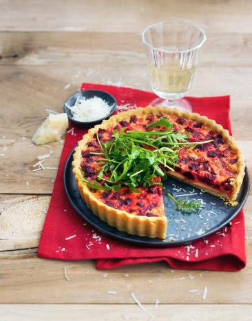 Quiche mit roter Bete und Rucola auf einem Servierteller.