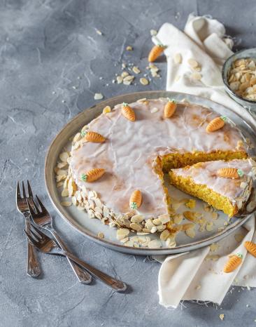 Karottenkuchen mit Zuckerguss auf einem Servierteller.