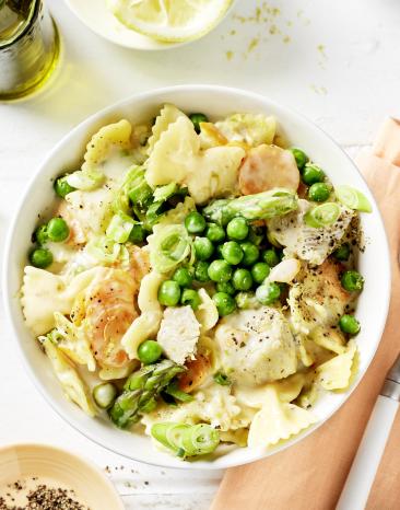 Nudeln, Erbsen und Hähnchen in Brühe in einer Schale.