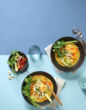 Gelbes Curry in zwei Schalen mit Koriander und Cashewkernen.