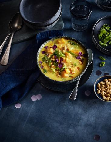 Gelbes Süßkartoffelcurry mit Kräutern in einer Schüssel.