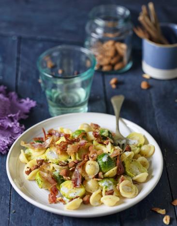Nudeln mit Rosenkohl und Speck auf einem Teller.