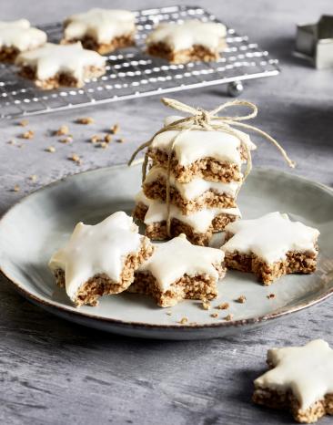 Zimtsterne auf eine Kuchengitter und grünem Teller.