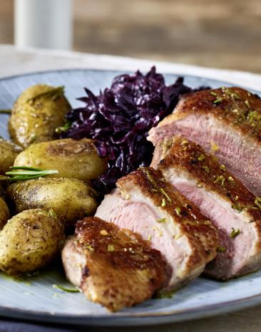 Entenbrust mit Rosmarin-Kartoffeln und Rotkohl auf einem Teller. Entenbrust mit Rosmarin-Kartoffeln und Rotkohl auf einem Teller.