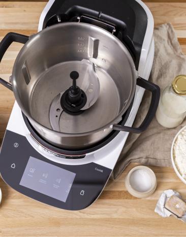 Cookit mit den Zutaten für einen Hefezopf daneben. Cookit mit den Zutaten für einen Hefezopf daneben.