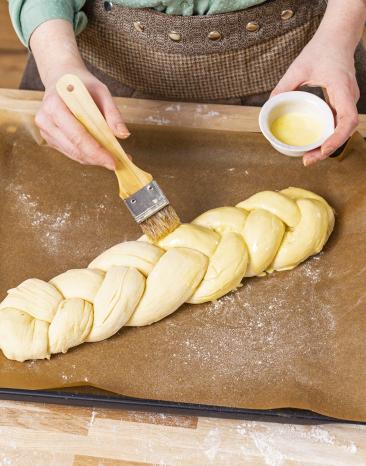 Hefezopf wird mit Gemisch bestrichen. Hefezopf wird mit Gemisch bestrichen.