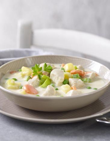 Eintopf mit Lauch, Kartoffeln und Geflügel in einem tiefen Teller.