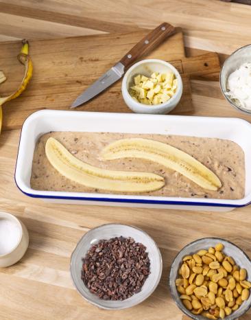 Bananenbrotteig in einer Brotform mit zwei halben Bananen belegt. Bananenbrotteig in einer Brotform mit zwei halben Bananen belegt.