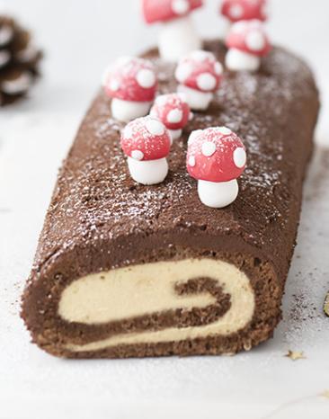Schokoladen-Biskuitrolle mit kleinen Pilzen dekoriert.