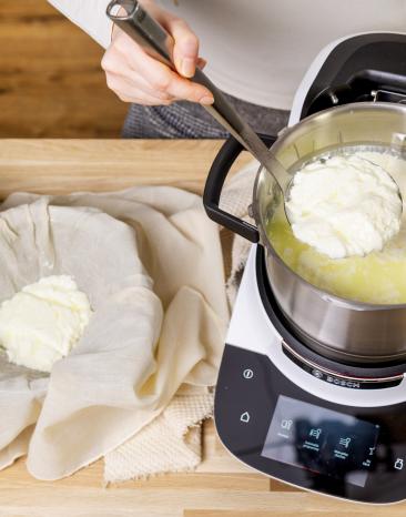 Mit einer Schöpfkelle hebst du die Käsemasse in eine mit Küchentuch ausgelegte Schale Mit einer Schöpfkelle hebst du die Käsemasse in eine mit Küchentuch ausgelegte Schale