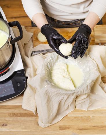 Aus der Käsemasse aus dem Cookit wird eine Mozzarellakugel von Hand geformt Aus der Käsemasse aus dem Cookit wird eine Mozzarellakugel von Hand geformt