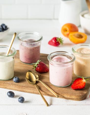 Fruchtjoghurt in Gläschen auf Brett mit Obst garniert.