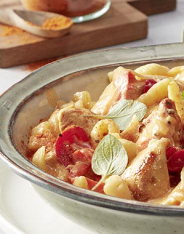 Ungarisches Hähnchen-Paprikasch mit Spätzle in einem tiefen Teller angerichtet.