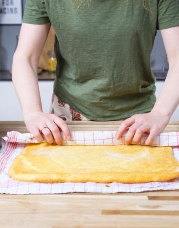 Biskuitteig wird in ein Handtuch gewickelt.