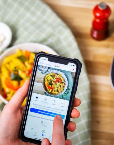 Cookit User klickt auf dem Handy in der Home Connect App auf einen Button Cookit User klickt auf dem Handy in der Home Connect App auf einen Button