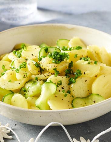 Bayrischer Kartoffel-Gurkensalat mit Schnittlauch in einer großen Schüssel.