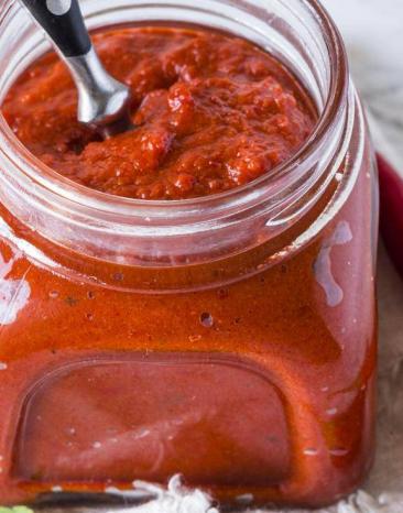 Harissa-Paste in einem Glas, daneben Gewürze auf dem Tisch Harissa-Paste in einem Glas, daneben Gewürze auf dem Tisch