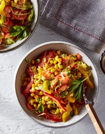 Bunter Mais in Schüssel mit Tellern daneben.