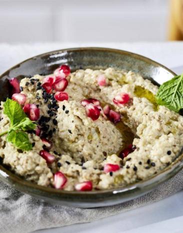 Creme aus Aubergine in einer Schale getoppt von Granatapfelkernen Creme aus Aubergine in einer Schale getoppt von Granatapfelkernen