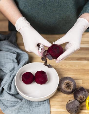 Rote Bete wird geschält, dabei trägt die Person Handschuhe Rote Bete wird geschält, dabei trägt die Person Handschuhe