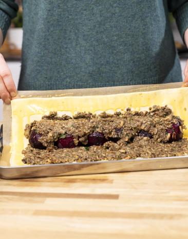 Der Blätterteig wird um die Füllung des Beet Wellington gelegt Der Blätterteig wird um die Füllung des Beet Wellington gelegt