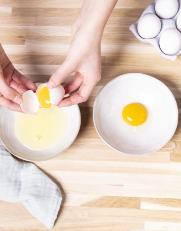 Eischnee im Cookit selber machen, Eier werden über einer Schüssel getrennt. Eischnee im Cookit selber machen, Eier werden über einer Schüssel getrennt.