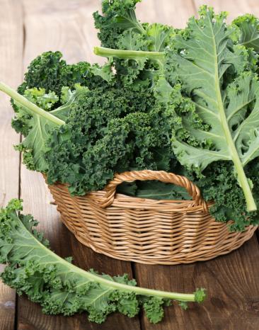 Grünkohlblätter in einem geflochtenen Korb auf einem Holzboden