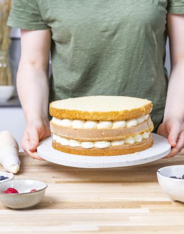 Hochzeitstorte in der Vorbereitung, drei Böden aufeinander gestapelt mit Sahnecreme. Hochzeitstorte in der Vorbereitung, drei Böden aufeinander gestapelt mit Sahnecreme.