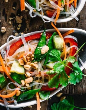 Asiatischer Glasnudelsalat in einer ovalen Schale mit üppiger Garnitur auf einem Tisch Asiatischer Glasnudelsalat in einer ovalen Schale mit üppiger Garnitur auf einem Tisch