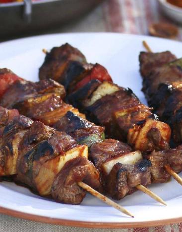 Vier bunte Schaschlikspieße nebeneinander auf einem weißen Teller