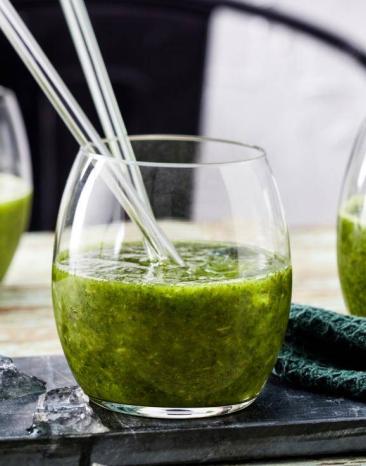Grünkohl-Detox-Smoothie in drei Gläsern mit Glasstrohhalmen auf einem Tisch Grünkohl-Detox-Smoothie in drei Gläsern mit Glasstrohhalmen auf einem Tisch