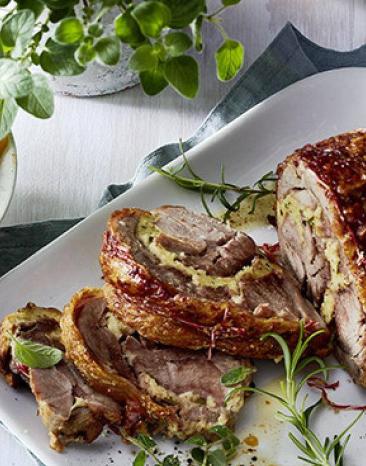 Putenrollbraten auf einer Platte daneben eine Schale Ratatouille auf einem Tisch Putenrollbraten auf einer Platte daneben eine Schale Ratatouille auf einem Tisch