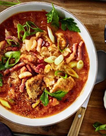 Eine Schale mit Schaschlik-Eintopf steht auf einem Holzbrett auf dem Tisch