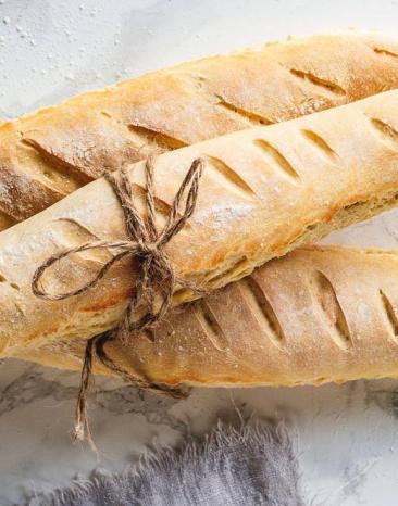 Drei Baguettestangen liegen zusammengebunden auf einer Marmorarbeitsplatte Drei Baguettestangen liegen zusammengebunden auf einer Marmorarbeitsplatte