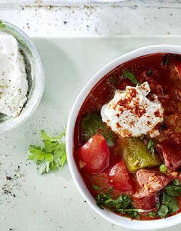 Spanische Linsensuppe in einem tiefen Teller, daneben eine Schale mit Schmand Spanische Linsensuppe in einem tiefen Teller, daneben eine Schale mit Schmand