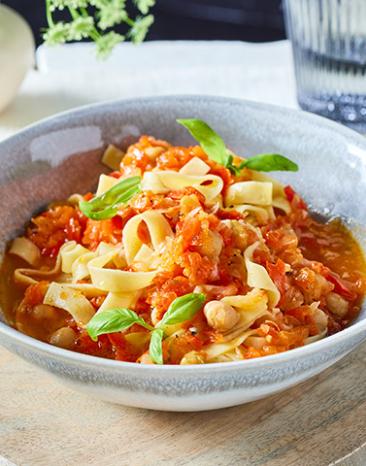 Turbo-Tagliatelle mit Paprika-Sugo mit Basilikum verziert in einer Schüssel.