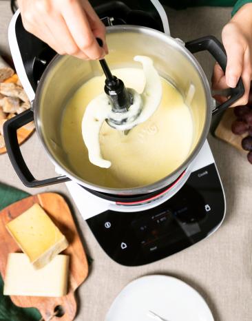Das Universalmesser wird aus dem mit Käsefondue gefüllten Cookit Kochtopf entfernt Das Universalmesser wird aus dem mit Käsefondue gefüllten Cookit Kochtopf entfernt