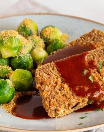 Nussbraten in Sauce mit Rosenkohl festlich arrangiert auf einem weißen Teller