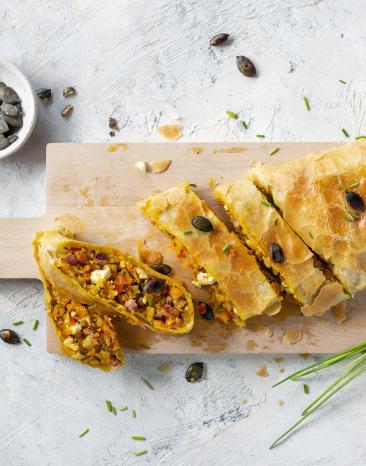 Angeschnittener Kürbisstrudel mit Feta, Speck und Kürbiskernen