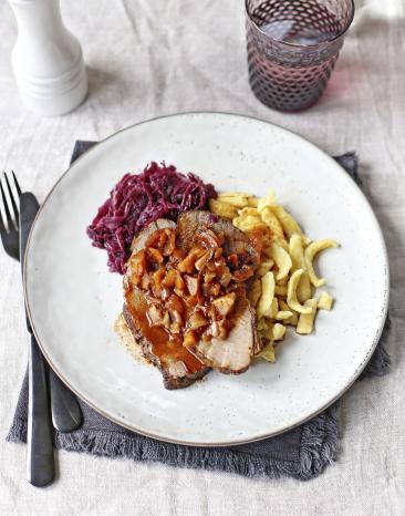 Braten mit Spätzle und Rotkohl auf Teller angerichtet.