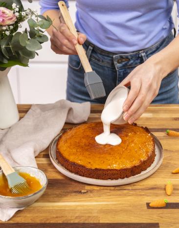Karottenkuchen wird mit Zuckerguss bestrichen. Karottenkuchen wird mit Zuckerguss bestrichen.