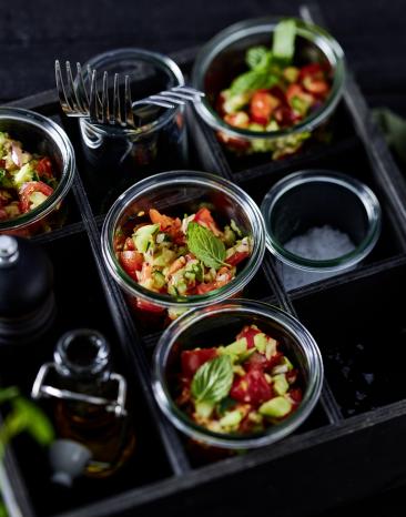 Tomaten Gurken Salat in kleinen Gläsern abgefüllt serviert.